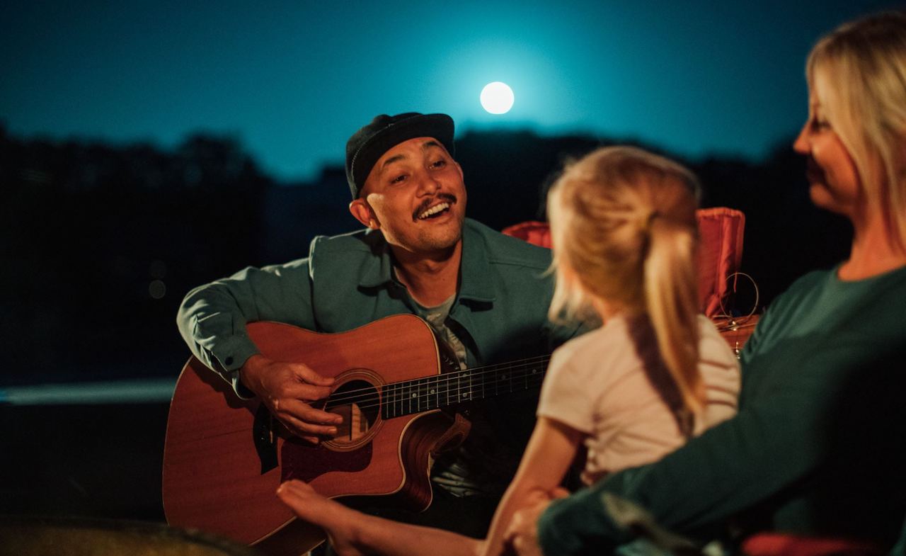 Man playing a guitar in McKinney Falls State Park Campground