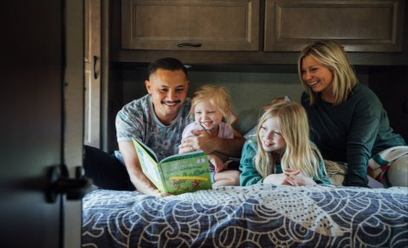 Family with young kids reading a book